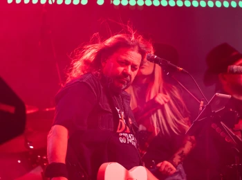 a man playing guitar on stage with a woman in the background